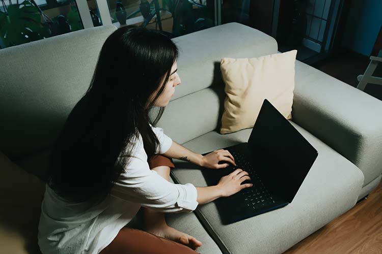 一个人坐在沙发上用笔记本电脑办公
